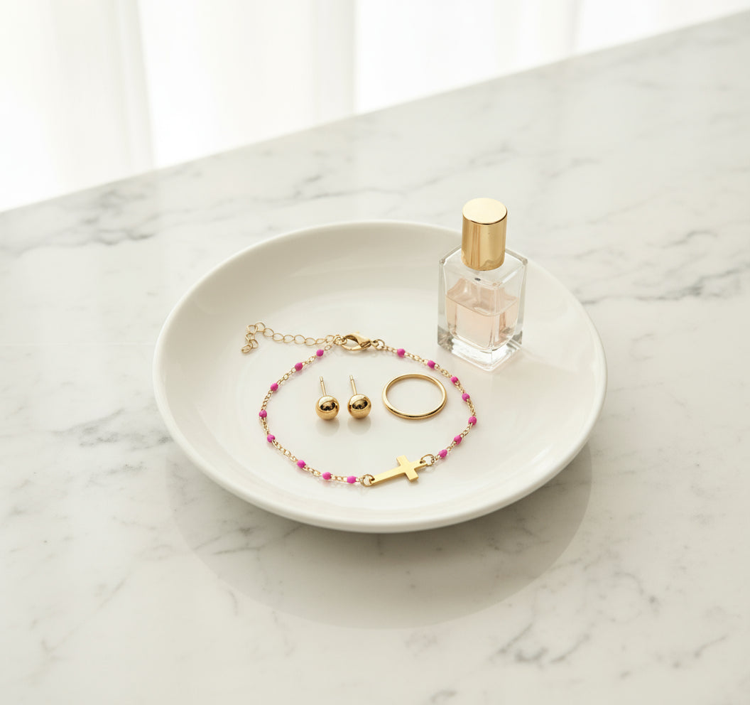 Gold bracelet with pink beads and a cross on a beige background