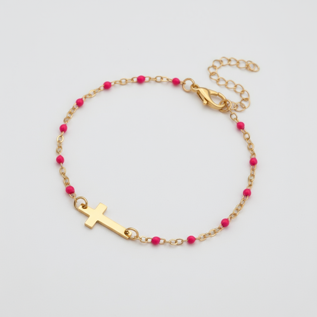 Gold bracelet with pink beads and a cross charm on a white background