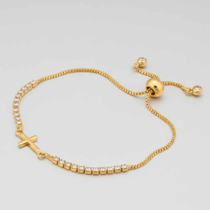 Gold bracelet with a cross charm on a light gray background