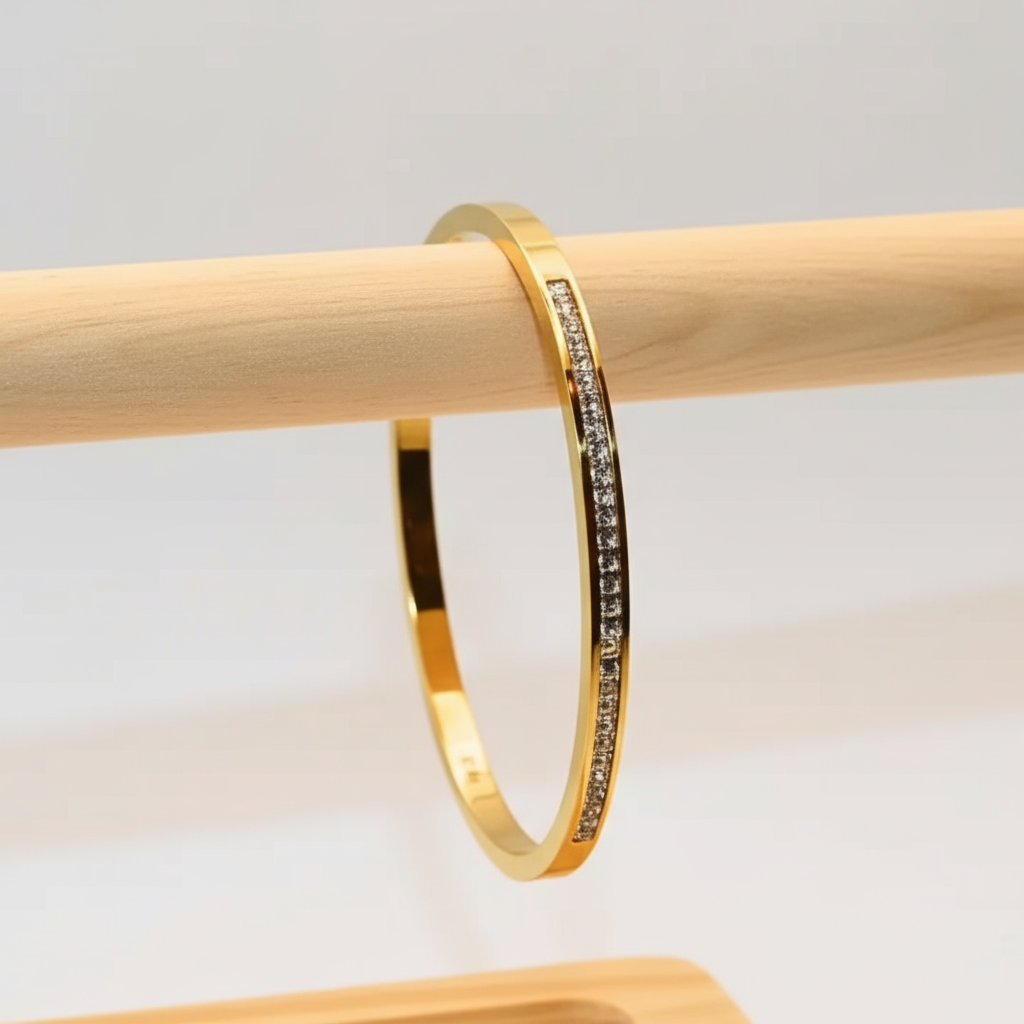 Gold bracelet with embedded stones on a wooden stand against a light background